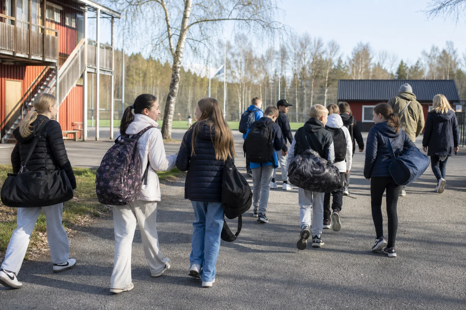 Skolklass på väg till idrottsanläggning med ryggsäckar